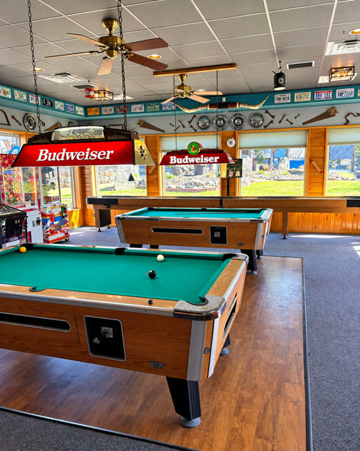 Pool tables under Budweiser lights in the arcade room